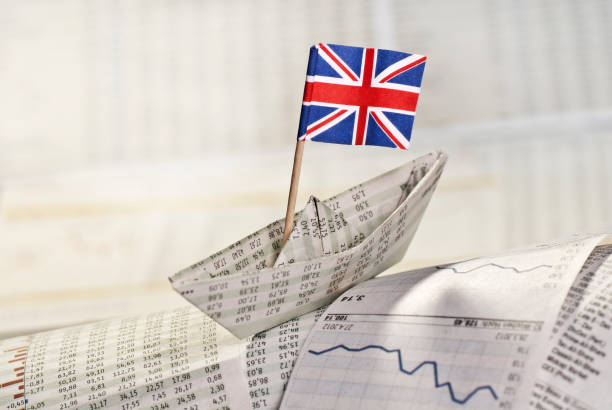 Symbol photo British economy Paper ship with British flag on newspaper pages with course tables. europa mythological character photos stock pictures, royalty-free photos & images