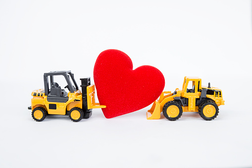 Forklift truck and front loader truck moving red heart, love industry concept