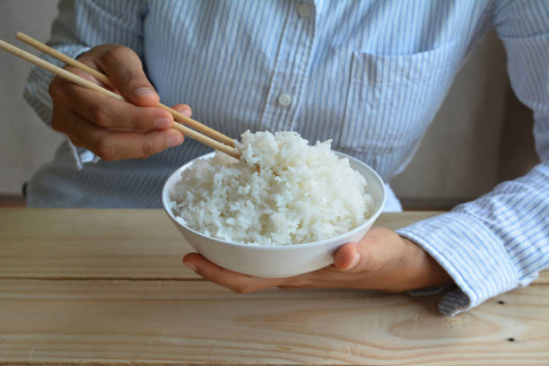 istock female hand hold Rice in white bowl with chopsticks 828428716