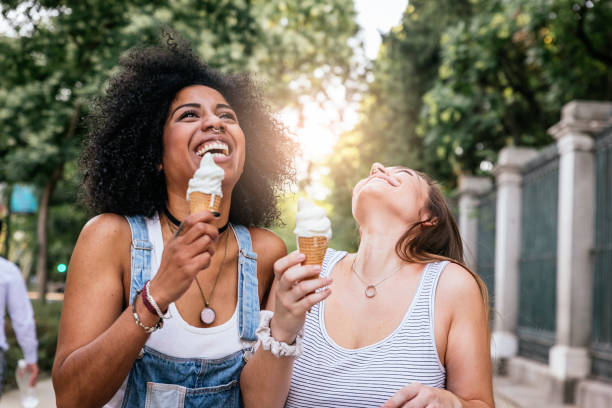 belle donne che mangiano un gelato per strada. - homosexual homosexual couple black ethnic foto e immagini stock