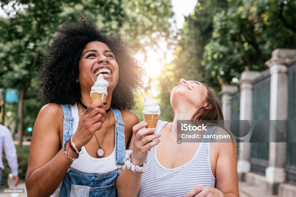 Beautiful women eating one ice cream in the street. Beautiful women eating one ice cream in the street. Youth concept. Ice Cream Stock Photo