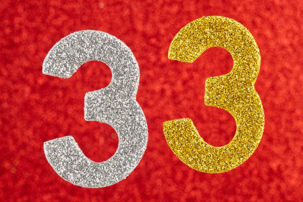 istock Number thirty-three yellow silver color over a red background. 828437252
