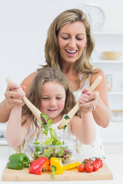 istock Mother and daughter mixing salad 828437388