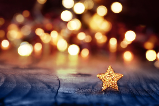 Festive background for christmas with golden lights and a star on a blue wooden table