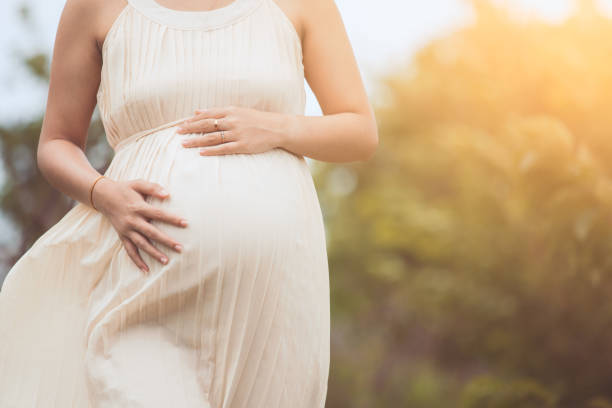 mujer embarazada tocar su vientre grande y caminar en el parque - holding belly fotografías e imágenes de stock