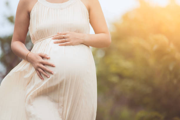 Pregnant woman touching her big belly and walking in the park Pregnant woman touching her big belly and walking in the park relaxing in outside bumpy photos stock pictures, royalty-free photos & images