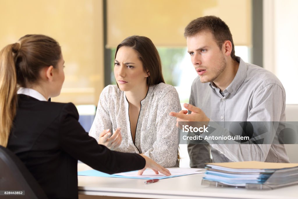 Couple claiming to a businesswoman at office Angry couple claiming to a businesswoman at office Customer Stock Photo
