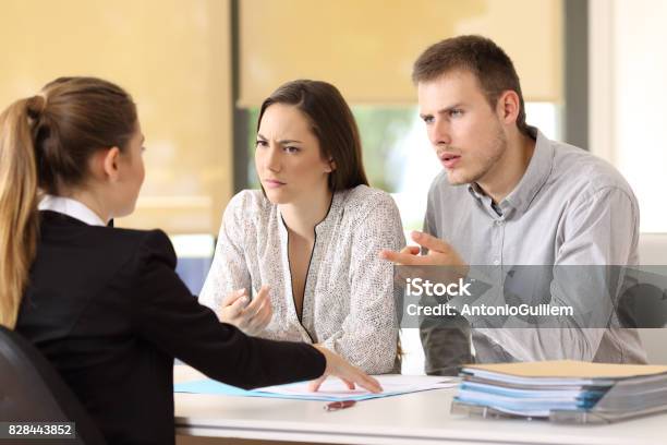 Couple Claiming To A Businesswoman At Office Stock Photo - Download Image Now - Assertiveness, Customer, Insurance