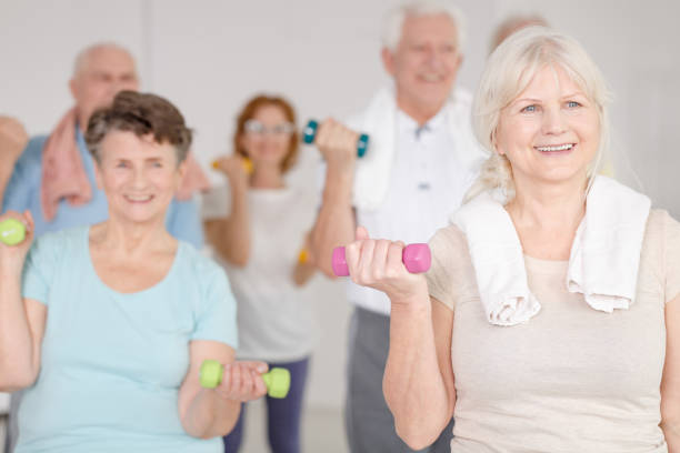 Working out with dumbbells Elder happy people working out with colorful dumbbells exercise class stock pictures, royalty-free photos & images