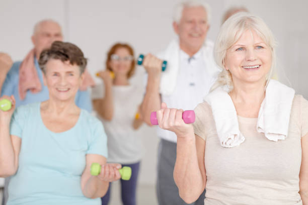 working out with dumbbells - fun senior adult aerobics exercise class imagens e fotografias de stock