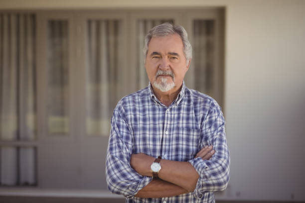istock Senior man standing with arms crossed at home 828448254