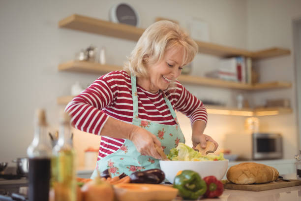 istock Senior woman mixing vegetables salad in kitchen 828448426