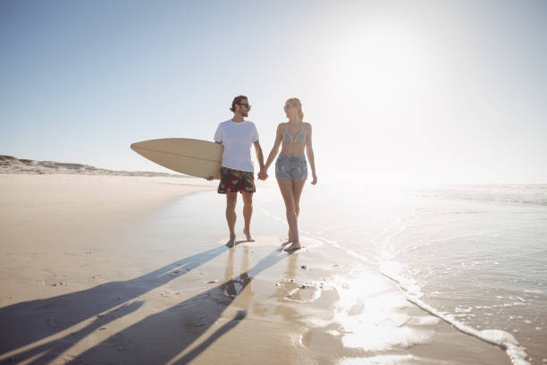 istock Young couple holding hands at beach during sunny day 828452532