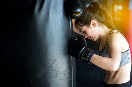 sexy fighter girl in gym with boxing bag. Long hair woman fitness