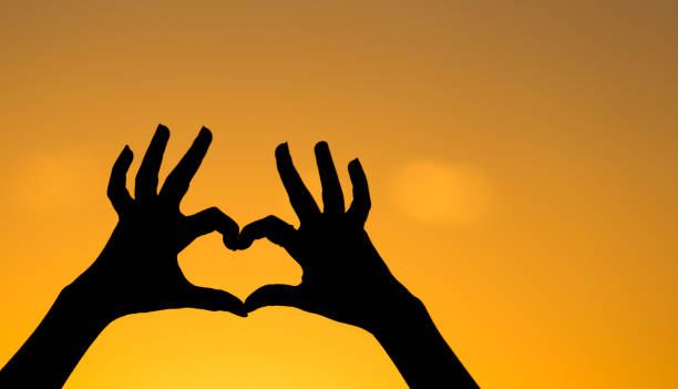 istock Silhouette of the heart by hands at sunset 828456178