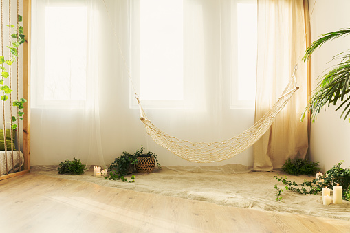 Natural hipster chillzone with sand and hammock in bright apartment
