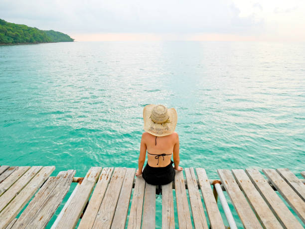 istock Woman with sunburned back sit on wooden jetty 828461456