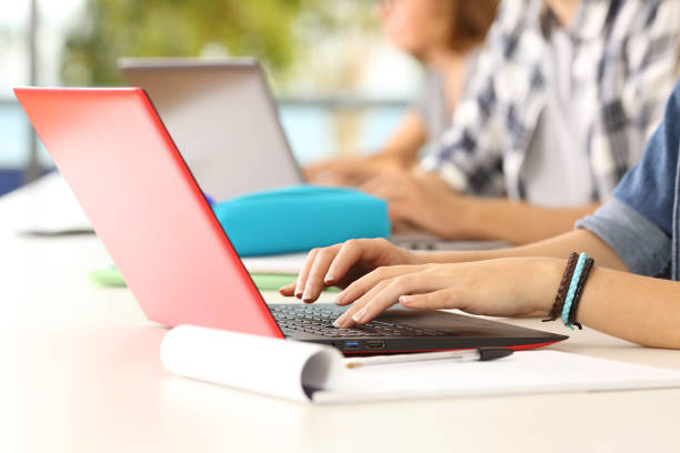 Hands of students learning on line in a classroom