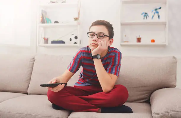 Photo of Bored teenage boy watching tv at home