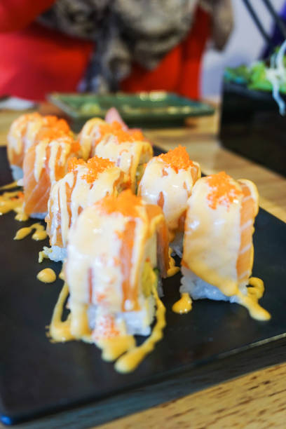 istock Sushi salmon roll with topped spicy sauce on black dish 828468038