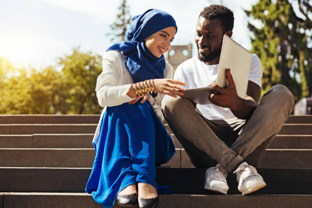 Wonderful admirable woman reading an article her friend suggesting Appreciating the hard work. Motivated intelligent enthusiastic guy asking for his friends opinion while sharing something interesting with her using his laptop final round stock pictures, royalty-free photos & images