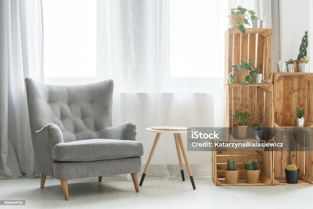 Shelf made of wooden boxes Modern shelf made of wooden boxes next to grey armchair Ethereal Stock Photo