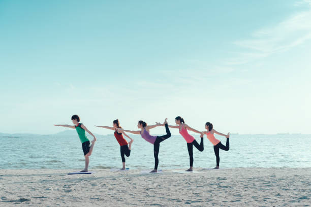 istock Young group yoga exercise practice  with pose on the beach relax vacation in summer 828469694