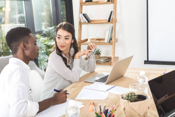 istock business colleagues discussing work while sitting at workplace in office 828470336