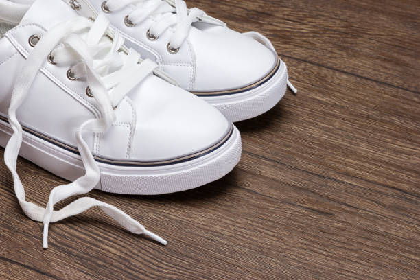 istock White sneakers on dark wooden surface 828473650