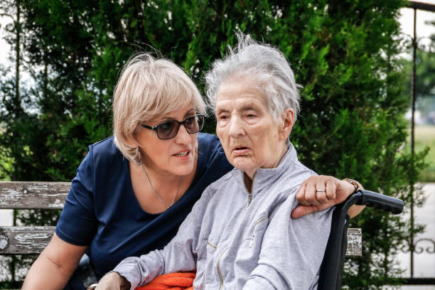 Mother ans daughter outdoors. Senior woman in wheelchair.