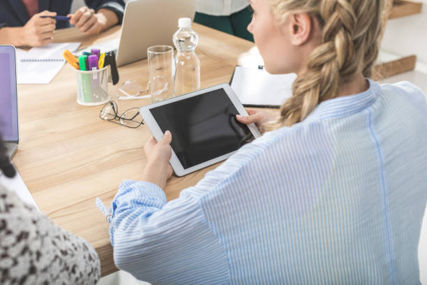 istock businesswoman holding digital tablet while sitting at table during meeting 828477026