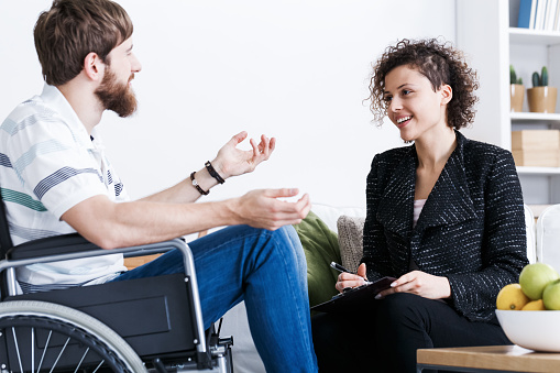 Young bearded man on wheelchair during home psychotherapy