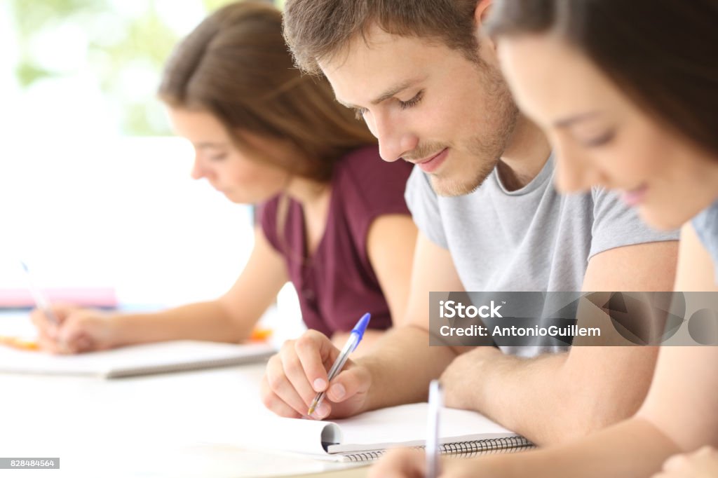 Close up of students taking notes at classroom Close up of three students studying taking notes at classroom Adolescence Stock Photo