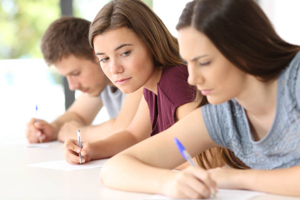 istock Student trying to copy an exam of a classmate 828484860