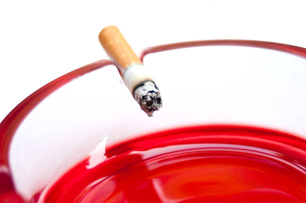 cigarette on the edge of the red ashtray - cigarette smoking ashtray tobacco imagens e fotografias de stock