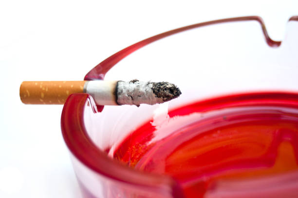 cigarette on the edge of the red ashtray - cigarette smoking ashtray tobacco imagens e fotografias de stock