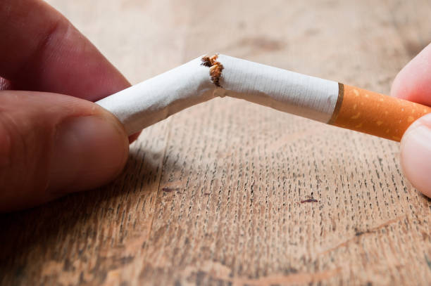 man broken a cigarette  on wooden table background - cigarette smoking ashtray tobacco imagens e fotografias de stock