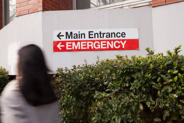 Hurrying to Emergency A woman hurries to the emergency entrance to the hospital. hospital emergency sign stock pictures, royalty-free photos & images