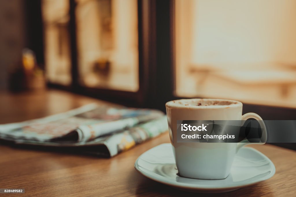 Capuccino coffee and newspaper on wooden table the windows background Newspaper Stock Photo