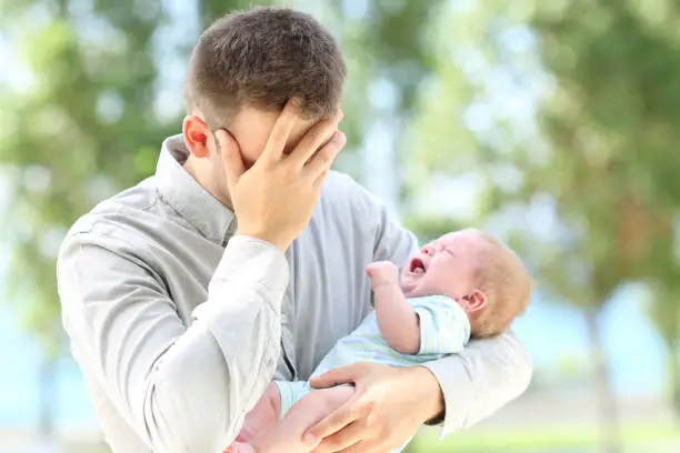 Photo of Worried father and baby crying