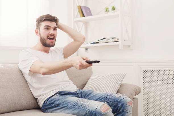 istock Worried young man wathing tv at home 828515736