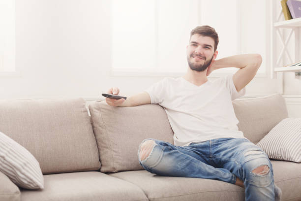 istock Young man in casual wathing tv at home 828515926
