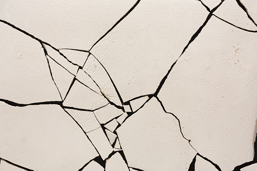 Fractured white concrete background. Old cracked plaster floor top view, copy space