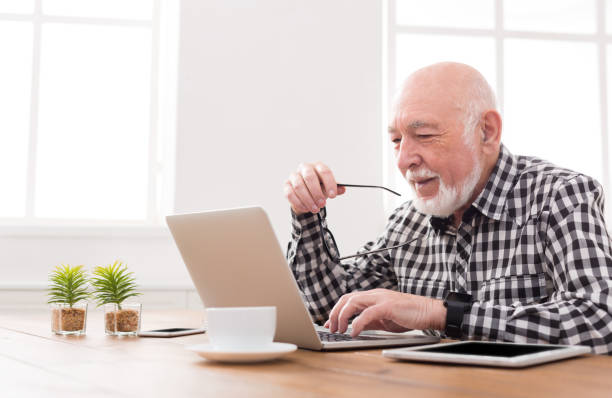 uśmiechnięty starszy mężczyzna za pomocą miejsca na kopiowanie laptopa - computer old men laptop zdjęcia i obrazy z banku zdjęć