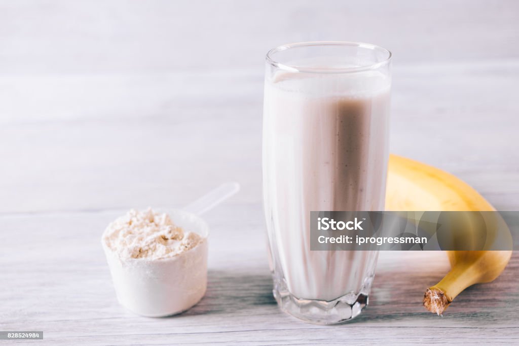 Protein cocktail in a glass, scoop and banana on a white wooden table Protein cocktail in a glass, scoop and banana on a white wooden table close-up Blended Drink Stock Photo Protein cocktail in a glass, scoop and banana on a white wooden table Protein cocktail in a glass, scoop and banana on a white wooden table close-up Blended Drink Stock Photo