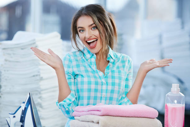 Woman near heap of rose towels and ironing board stock photo