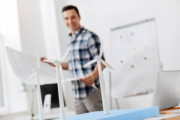 istock Architect holding a blueprint and looking at wind turbine models 828526622