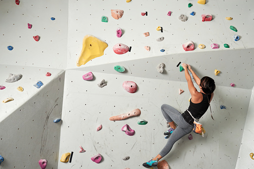 Sporty young woman climbing indoors,