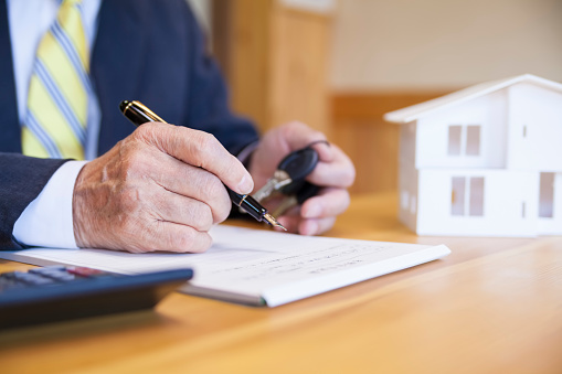 A Japanese businessman is filling in the contract for selling a new house.