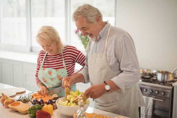 istock Smiling senior couple preparing salad in kitchen 828550972